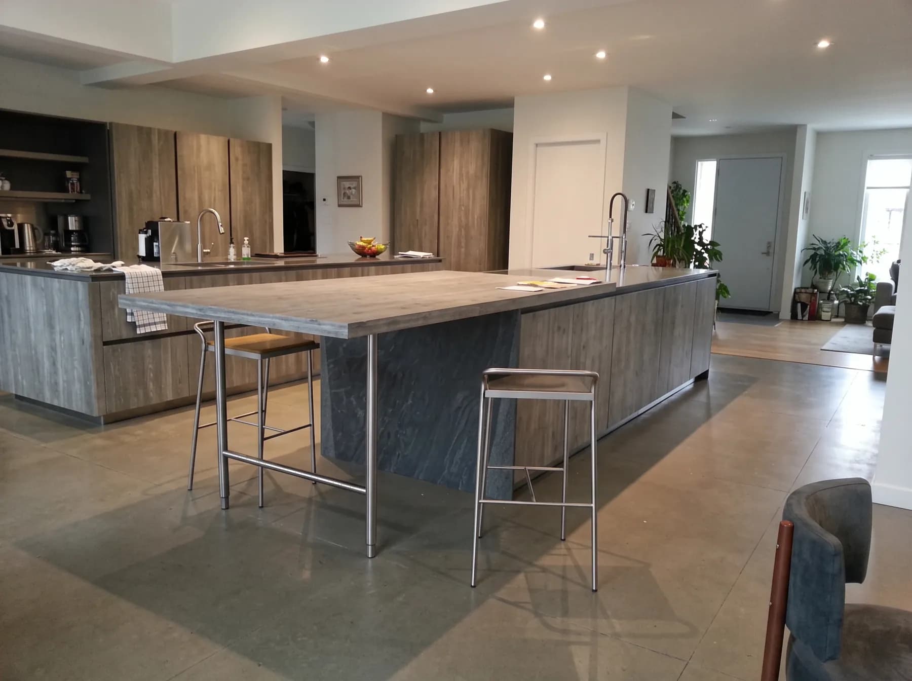 Grey stone island beside timber cabinetry in an open-plan kitchen