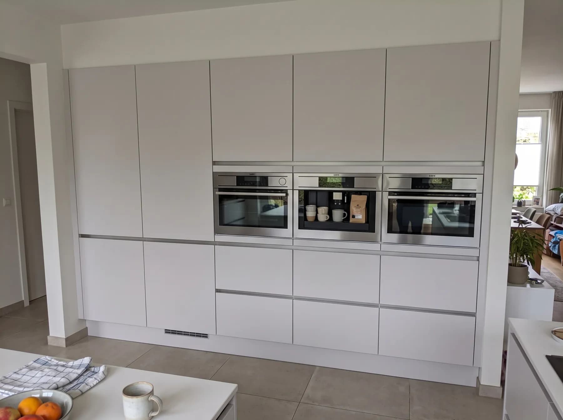 Tall off-white units with integrated ovens and a built-in coffee machine
